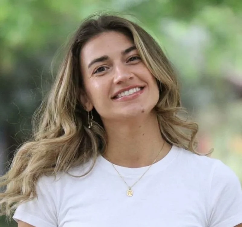 Keren smiling outdoors in front of green trees